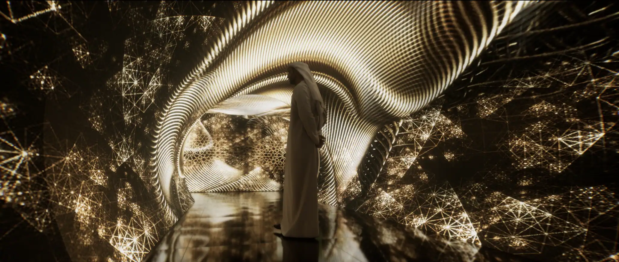 Visitor beneath a gold light installation at the Aramco Symposium