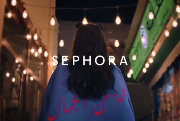 A woman walking through a lit street market at night, with Sephora titling